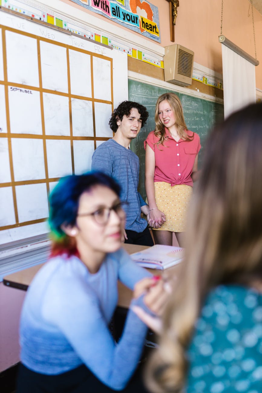 Two secondary school students stand at the front of a classroom presenting to their peers.